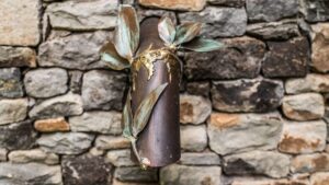 Metal pipe with leaf design on stone wall.
