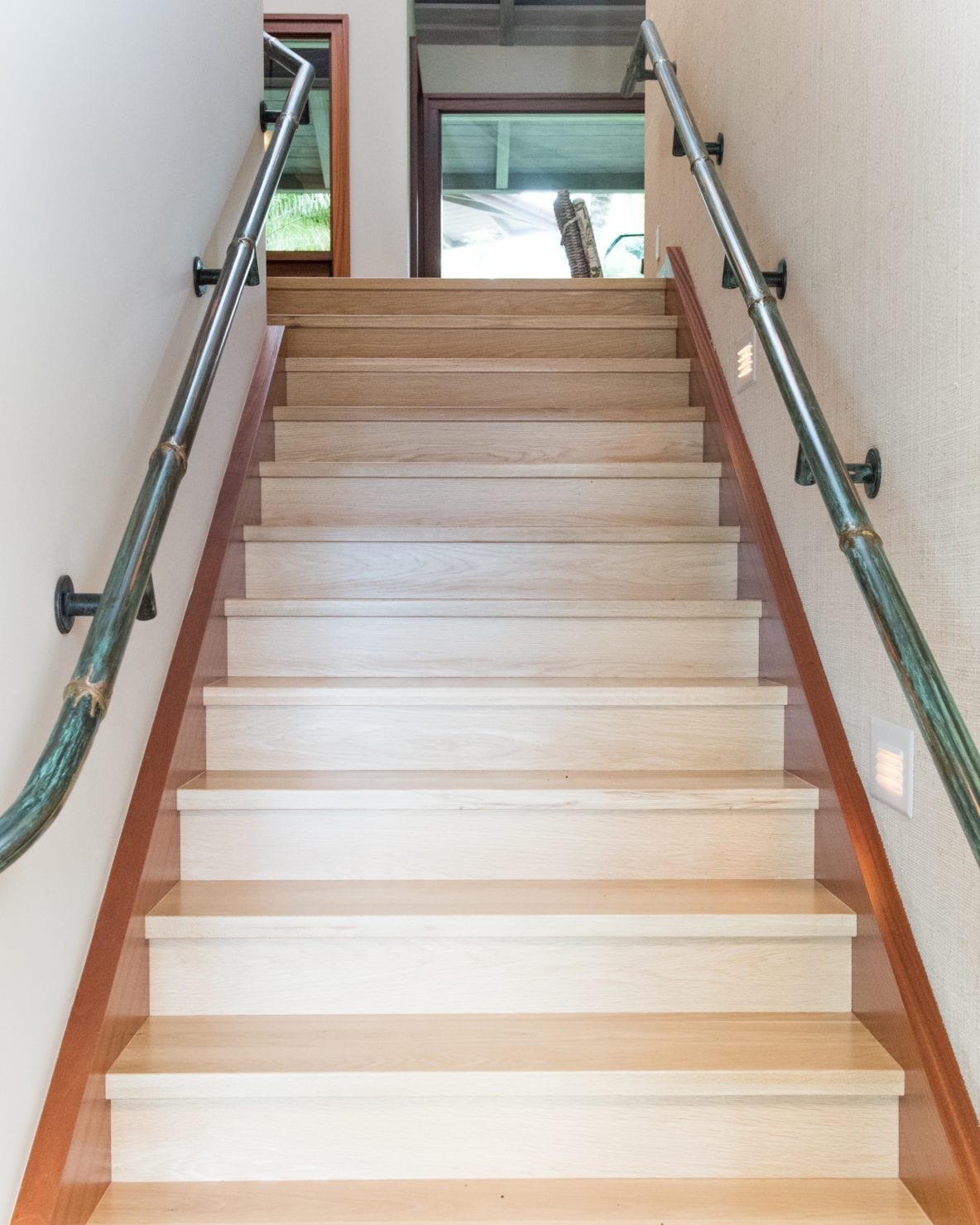 Modern wooden staircase with green handrails and natural light.