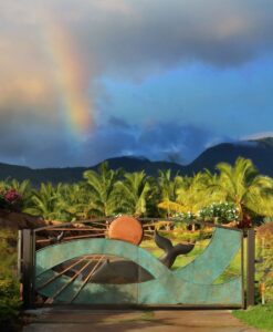 Decorative gate with rainbow and palm trees.