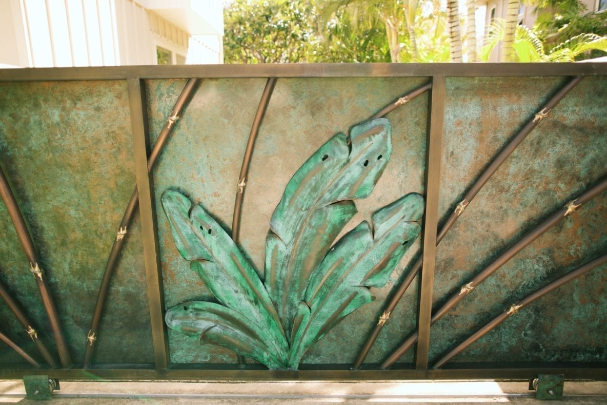 Metal gate with decorative leaf design in green patina.