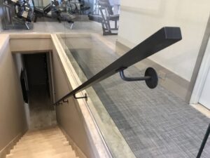 A sleek black handrail along a stairway in a modern building.