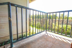 Empty balcony with black metal railing overlooking greenery.