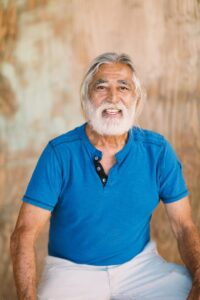 Smiling man in blue shirt, seated indoors.