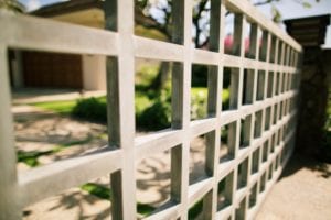 Close-up of a white metal grid fence with a blurred background.
