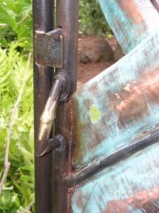 Close-up of a rusty hinge on a weathered metal door with patina.