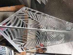 Metal panel with intricate palm leaf design, ready for installation.