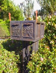 Rustic metal mailbox numbered 25 in a garden.