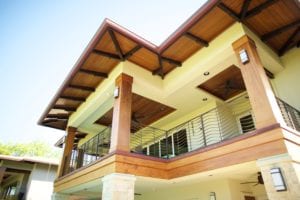 Modern house balcony with wooden and glass elements under a clear sky.