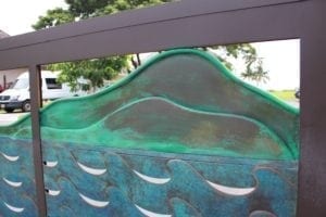Green-tinted glass sculpture with wave patterns and a mountain silhouette.
