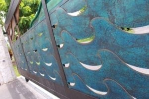 Decorative metal panel with fish-shaped cutouts and a weathered blue-green patina.