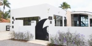 Modern white building with a black shark fin-shaped gate and lavender plants.