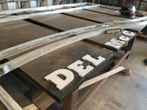 Wooden signs with white letters spelling 'DEL' laid out on a table.