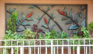 Decorative metal wall art with plants and red chili accents.