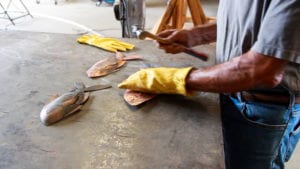 Person cleaning fish with a glove on one hand at a market stall.