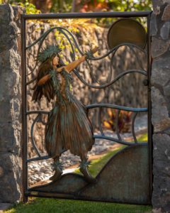 A decorative metal sculpture of a hula dancer on a gate.