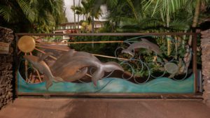 Artistic sculpture of a dragon intertwined with a serpent in a tropical setting.