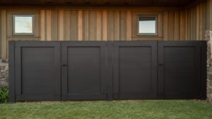 Modern dark brown garage doors on a wooden house exterior.