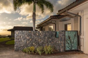 Modern house exterior at sunset with stone wall and palm tree.