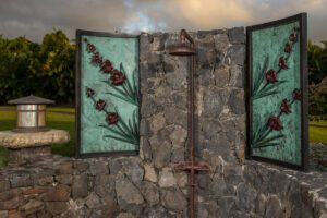 Outdoor stone shower with decorative stained glass panels and rain showerhead.