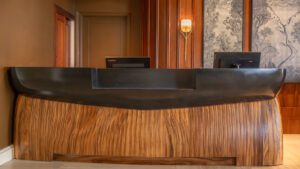 Elegant wooden reception desk with black accents in a warmly lit room.