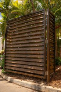 Wooden privacy screen with horizontal slats in a garden setting.