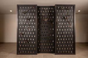 Three wooden panels with metal hooks arranged in a pattern.