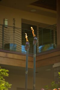 Two tiki torches with flames burning indoors near a railing.