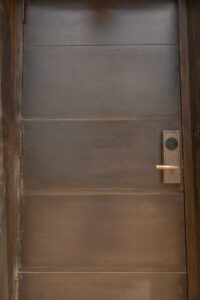 A rustic wooden door with a black handle and lock.