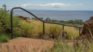 Rustic handrail alongside a pathway overlooking a coastal view.
