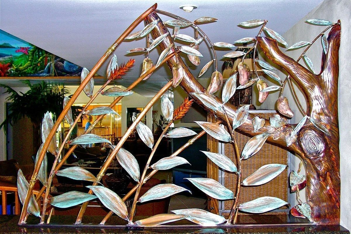 Metal sculpture of fish on branches displayed indoors.