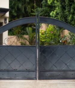 Black metal gate with a curved top and diamond pattern.