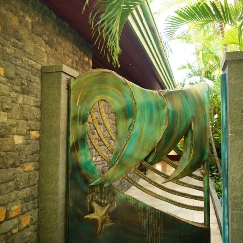 A bronze sculpture of a large cat climbing a fence in a garden.