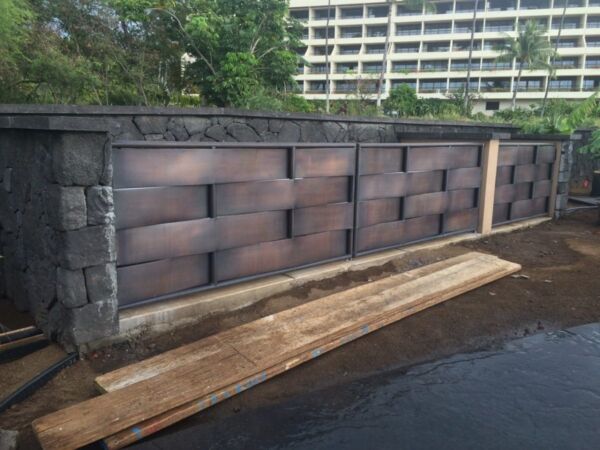 Modern concrete wall with a woven pattern design and wooden planks nearby.