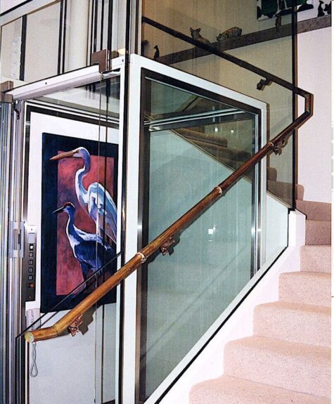 Modern staircase with a glass railing and wooden handrail next to a colorful bird painting.