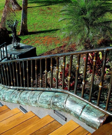 Curved outdoor staircase with a decorative metal handrail and lush greenery.