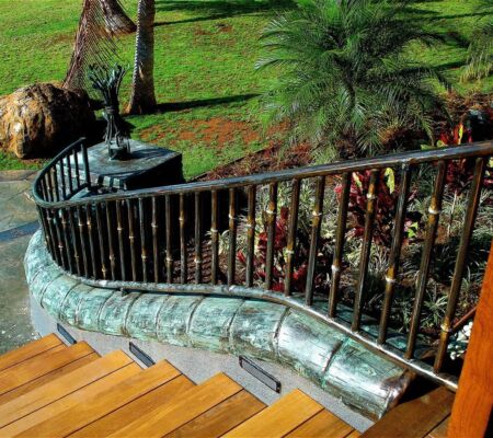 Curved glass railing with wooden stairs and greenery.