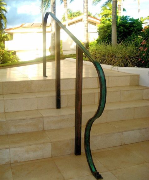Garden hose draped over outdoor stairs railing.