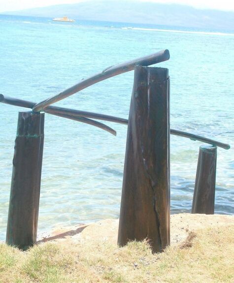 Rustic wooden posts near a clear blue sea shore.