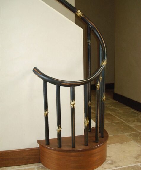 A stylish wooden and metal curved handrail with brass accents.