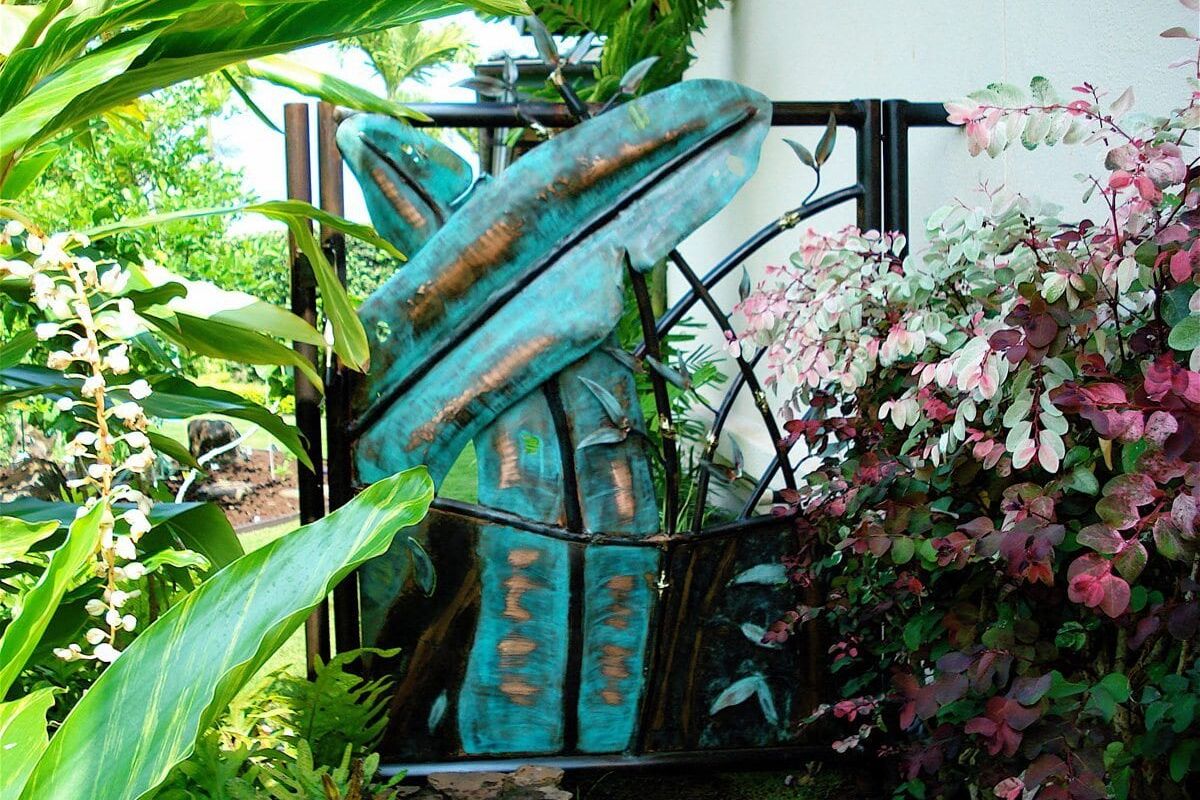 Artistic metal sculpture of fish in a garden setting.