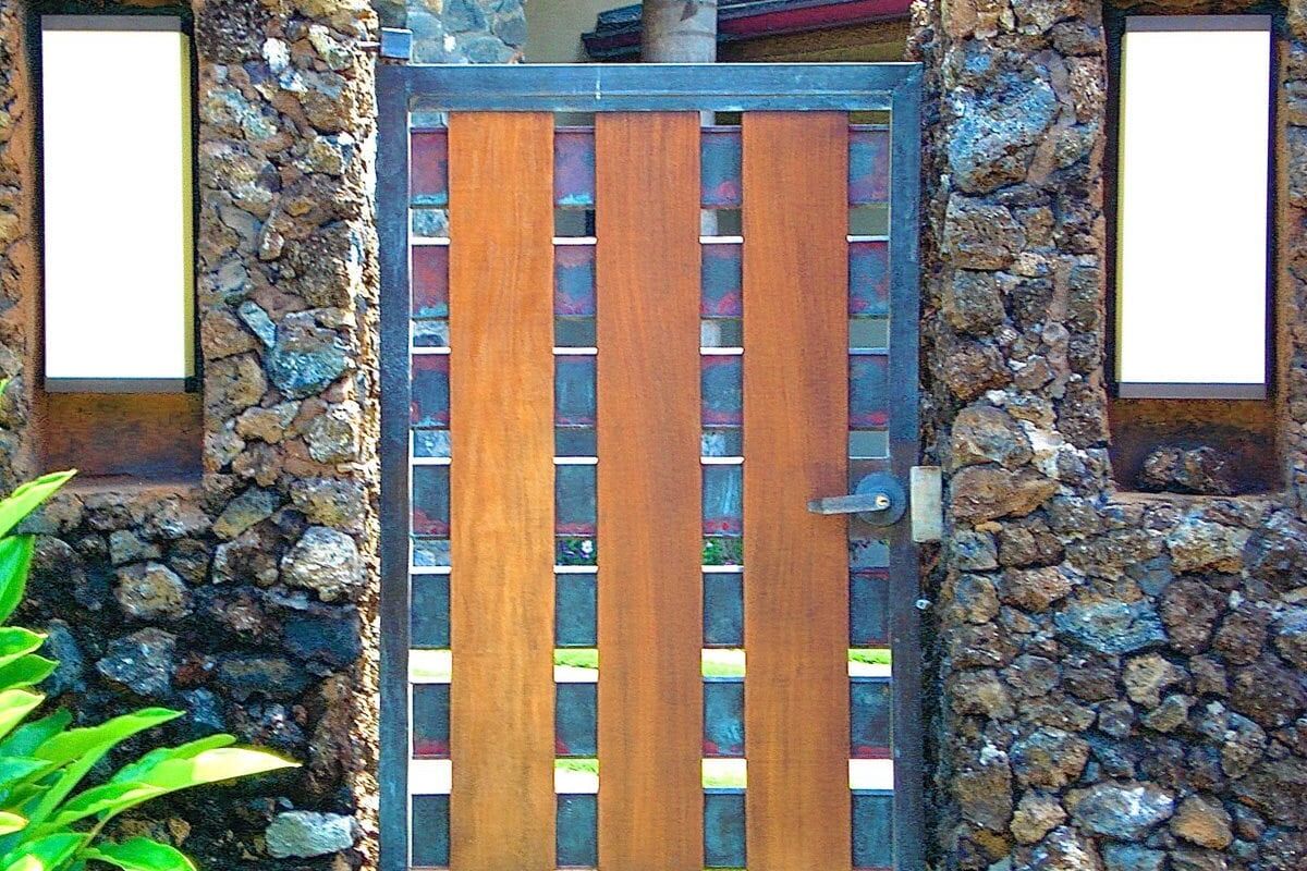 Modern wooden and metal gate set in a rustic stone wall.