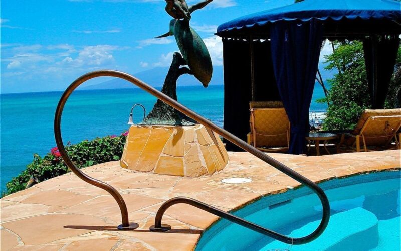 Elegant mermaid sculpture by a pool overlooking the ocean.