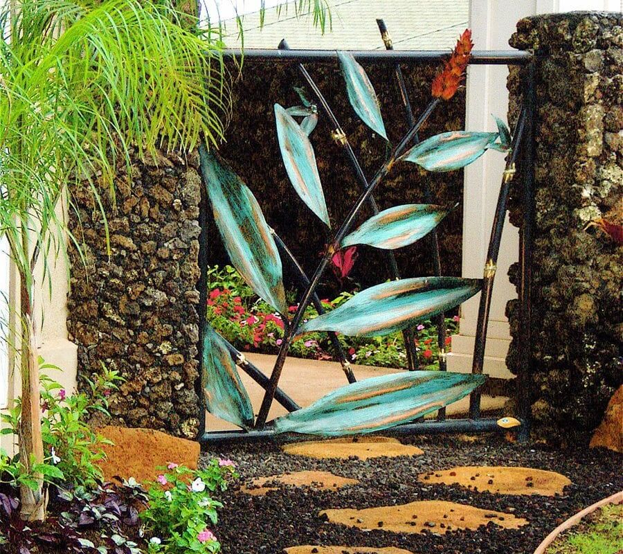 Decorative garden gate with leaf design and stone pillars.