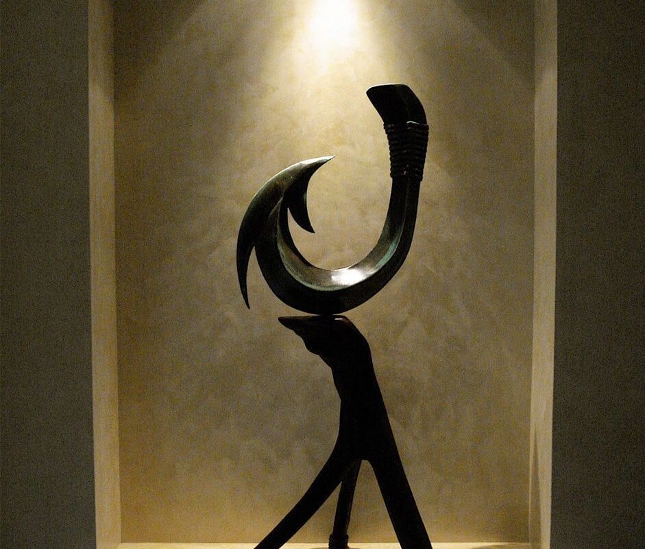 Abstract black sculpture with curved and angular shapes on a pedestal.