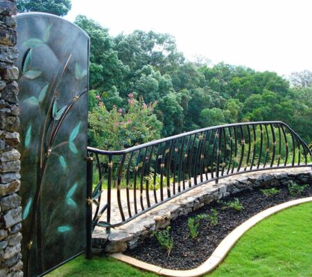 Curved metal railing along a garden pathway with lush greenery.