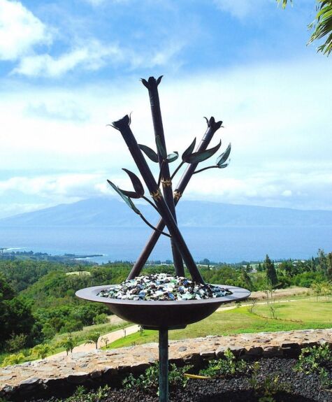 Modern metal sculpture set against a scenic outdoor backdrop.