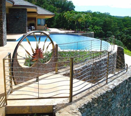 Outdoor pool area with decorative metal fencing and greenery.