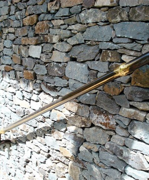 A brass water spout on a stone wall with water flowing out.