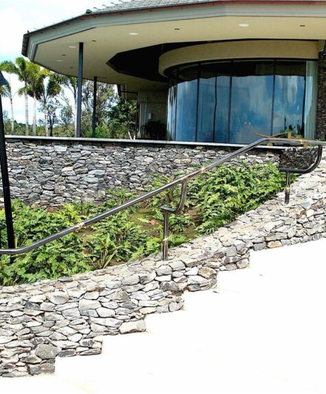 Modern building with curved glass and stone retaining wall.