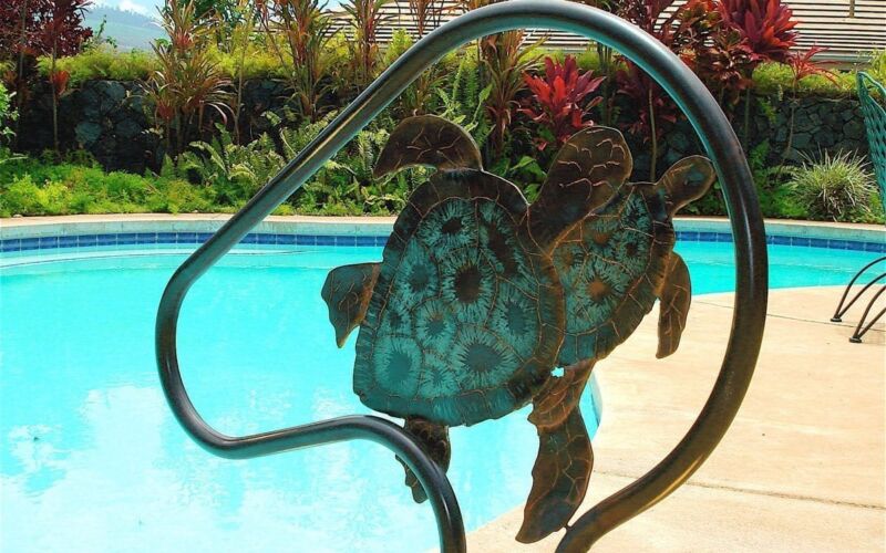 Artistic metal sea turtle sculpture by a poolside.